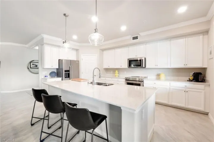 Kitchen featuring white cabinetry, pantry, pendant lighting, and upgraded stainless appliances.