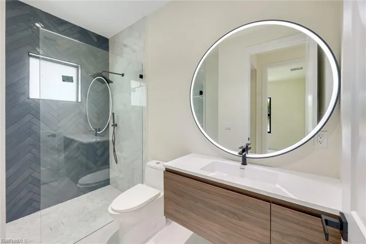 Gorgeous guest bathroom with marble shower tiles and LED mirrors.