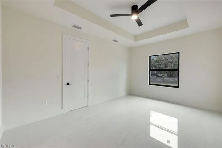 This spacious master bedroom features an elegant tray ceiling that adds depth and character, creating a serene and relaxing atmosphere, perfect for unwinding after a long day.