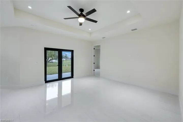 This spacious living room features elegant French doors that open to the outdoors, allowing natural light to flood the space and enhancing the overall atmosphere.