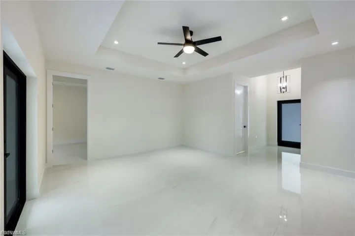 This spacious living room features elegant tray ceilings and plenty of natural light, creating a bright and airy atmosphere. The open layout and neutral tones offer a modern, welcoming feel, perfect for any home.