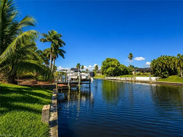 Waterfront property featuring a private boat dock, lush tropical landscaping, and clear canal access