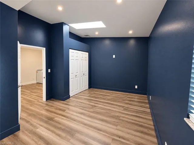 Wood-finish flooring, recessed lighting, skylight, and white bi-fold closet doors