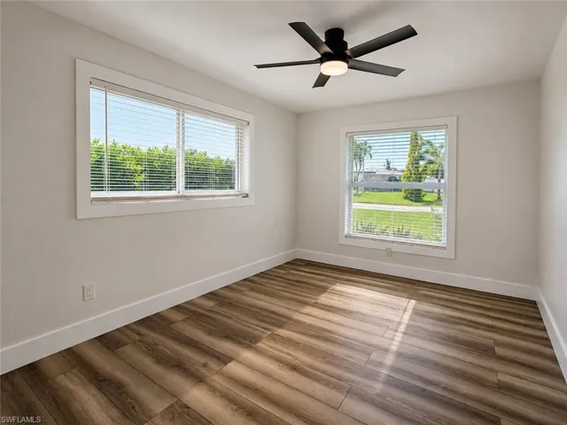 Wood-finish flooring, white walls, and a contemporary ceiling fan with integrated lighting