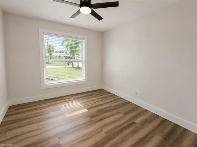 Wood-finish flooring, white walls, and a window with blinds