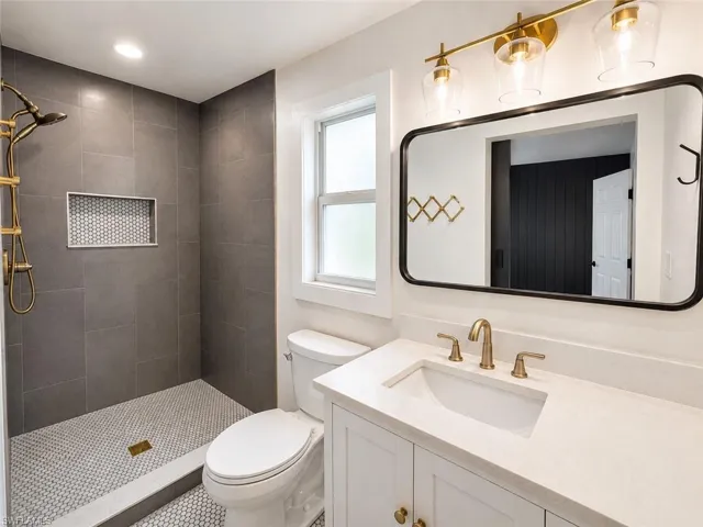 Contemporary bathroom featuring a walk-in shower with large format tile, a built-in shower niche, a single vanity with an integrated sink, and an overhead vanity light fixture