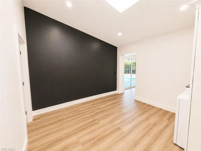 Wood-finish flooring, recessed lighting, and a skylight illuminate this living space