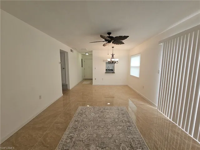 Unfurnished room featuring ceiling fan and a chandelier
