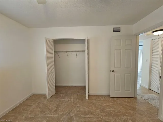 Unfurnished bedroom with a closet, a textured ceiling, and a ceiling fan