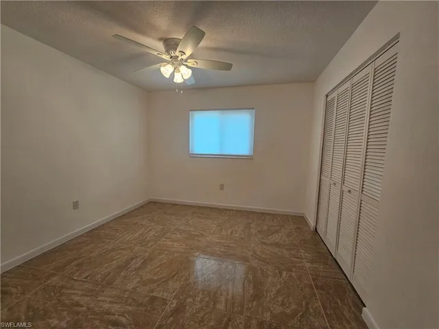 Unfurnished bedroom featuring a closet, a textured ceiling, and ceiling fan