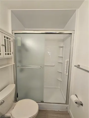 Full bath with a shower stall and dark wood-type flooring