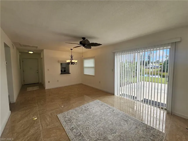Unfurnished living room with plenty of natural light, a textured ceiling, ceiling fan, and a chandelier
