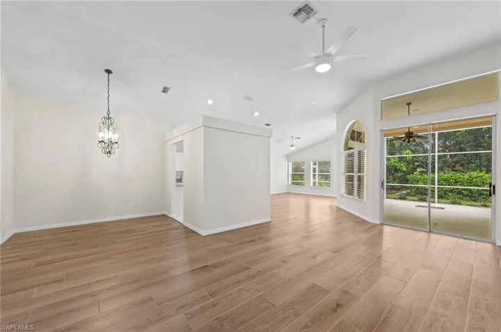 Unfurnished living room featuring lofted ceiling, recessed lighting, a chandelier, light wood-type flooring, and a ceiling fan