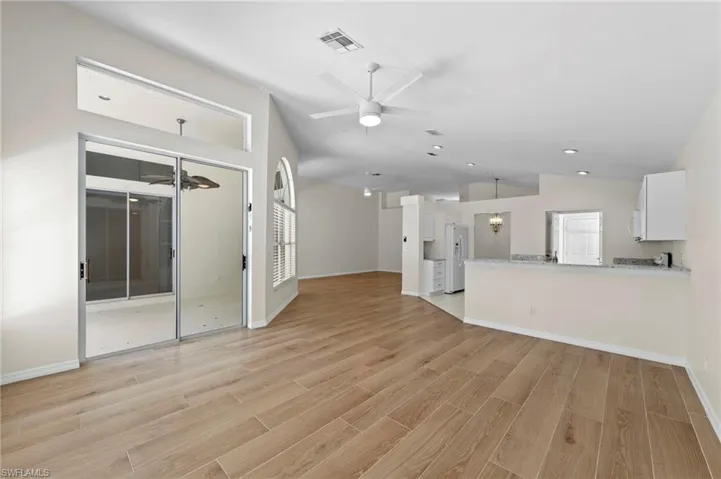 Unfurnished living room with a ceiling fan, lofted ceiling, light wood finished floors, and recessed lighting