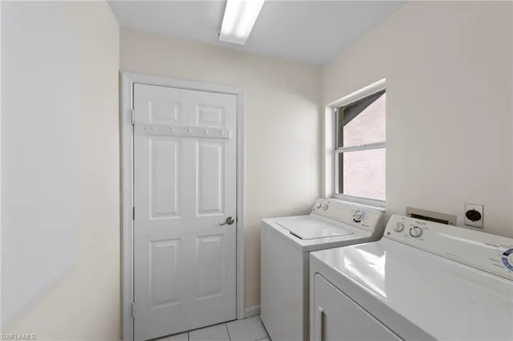 Washroom with light tile patterned flooring and independent washer and dryer