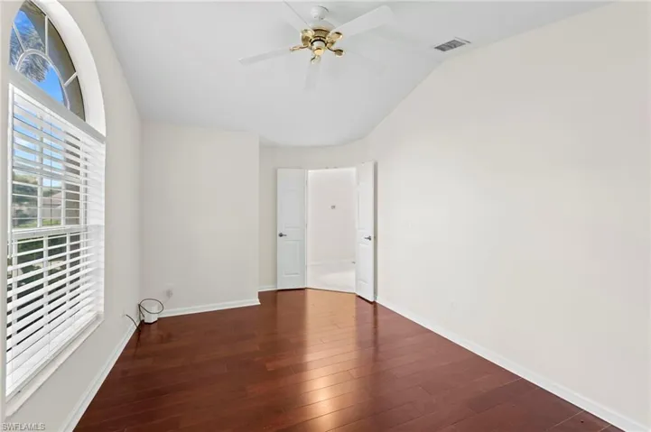 Empty room featuring dark wood finished floors, vaulted ceiling, and ceiling fan
