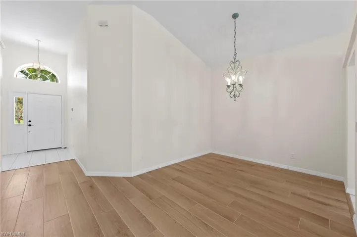 Entryway featuring high vaulted ceiling, a chandelier, and wood tiled floors