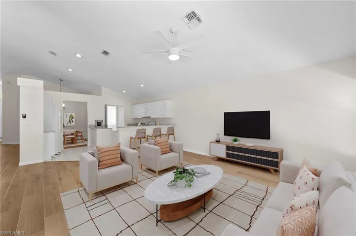 Living room with light wood-type flooring, lofted ceiling, ceiling fan, and recessed lighting