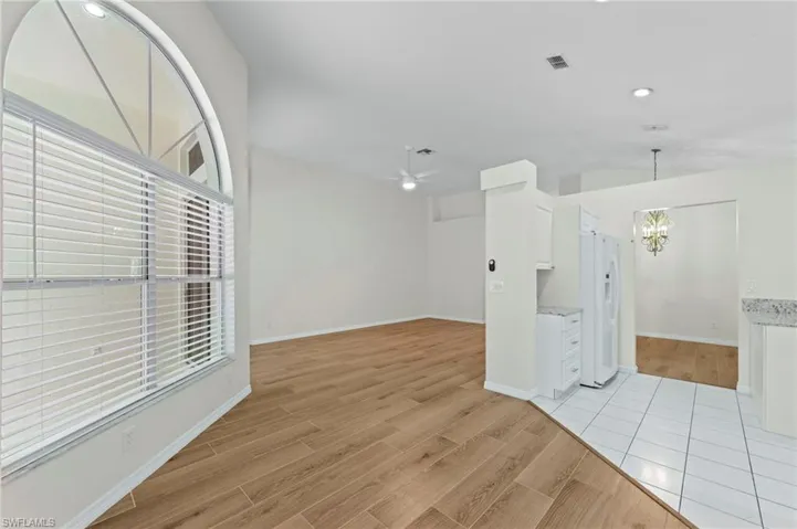 Spare room featuring a chandelier, a ceiling fan, light wood-type flooring, and recessed lighting