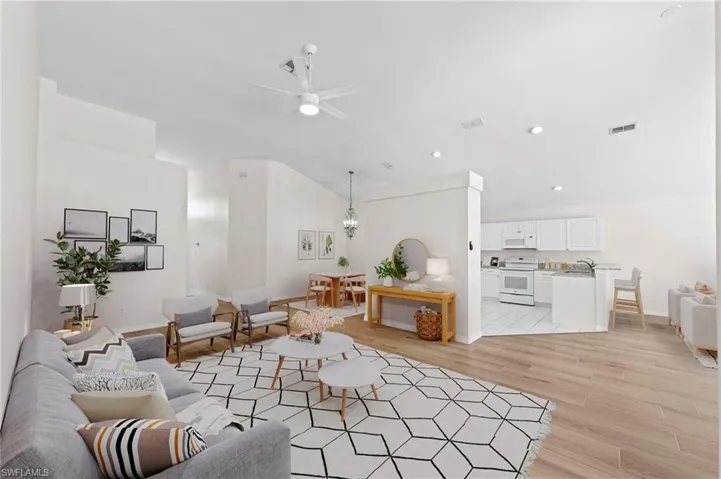 Living room featuring light wood-style flooring, ceiling fan, recessed lighting, and vaulted ceiling
