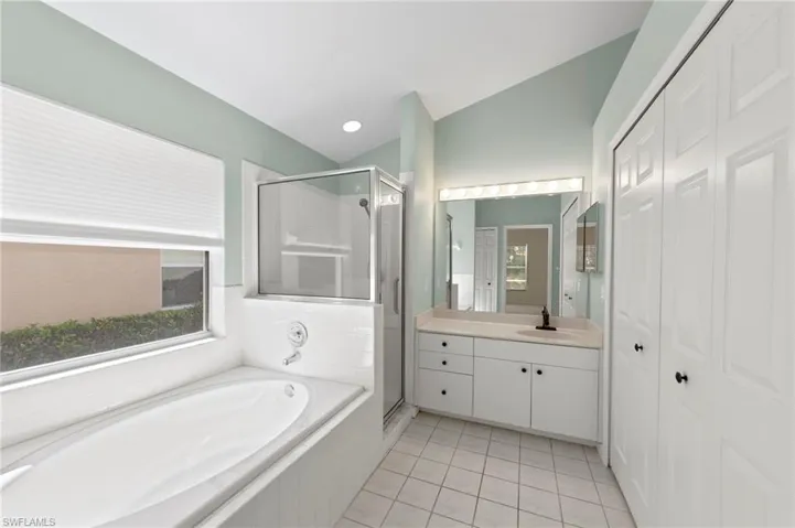 Full bathroom with a shower stall, vanity, a garden tub, light tile patterned flooring, and a closet