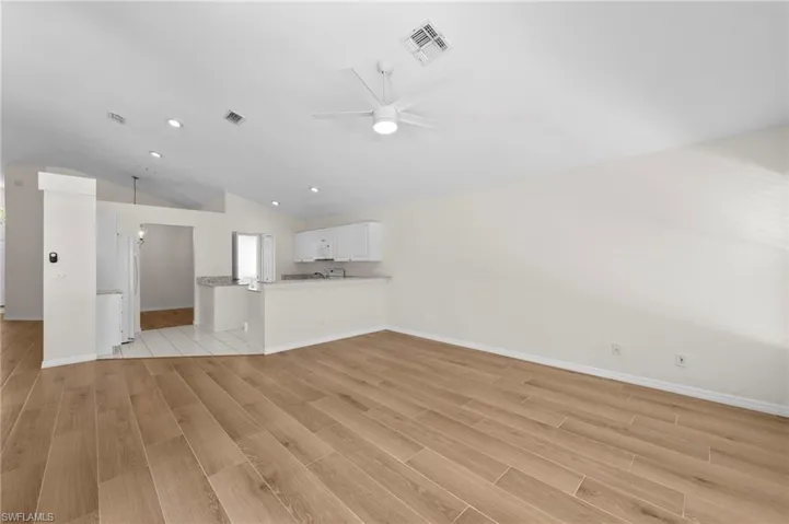 Unfurnished living room with vaulted ceiling, light wood-type flooring, ceiling fan, and recessed lighting