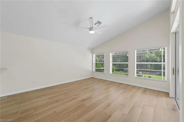 Empty room featuring lofted ceiling, light wood-style floors, and ceiling fan