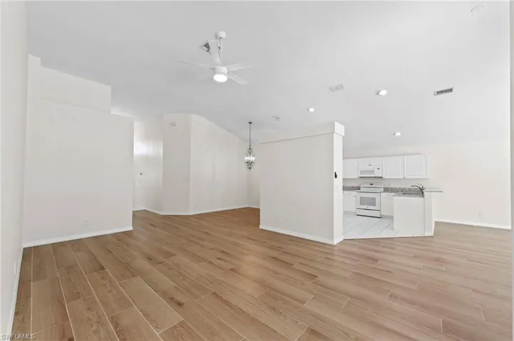 Unfurnished living room with a ceiling fan, light wood-style floors, a chandelier, and recessed lighting