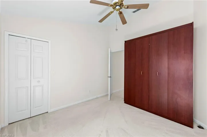 Unfurnished bedroom with light carpet and a ceiling fan