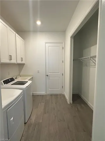 Clothes washing area featuring dark hardwood / wood-style floors, independent washer and dryer, sink, and cabinets