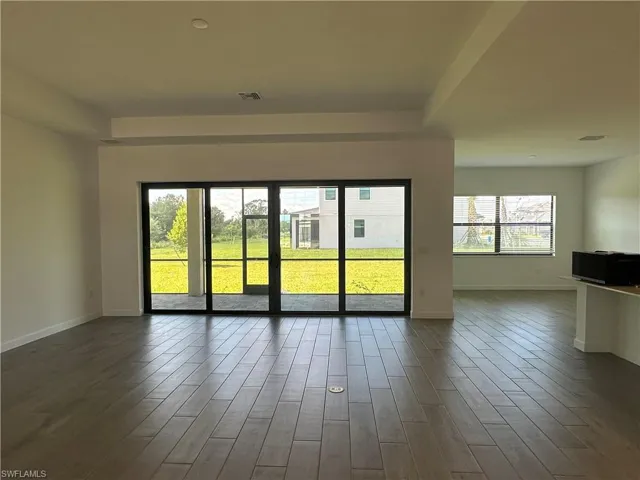 Empty room featuring a healthy amount of sunlight and dark hardwood / wood-style floors