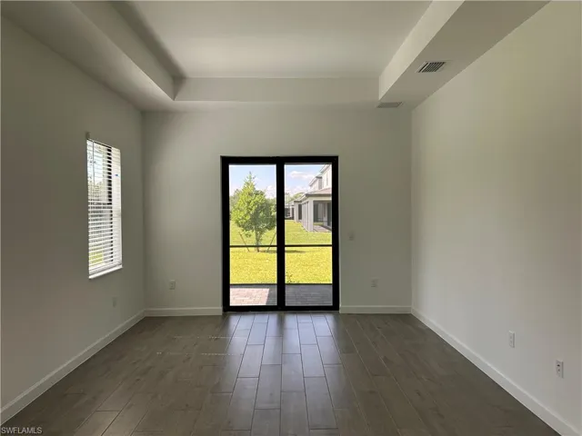 Unfurnished room with dark wood-type flooring and a tray ceiling