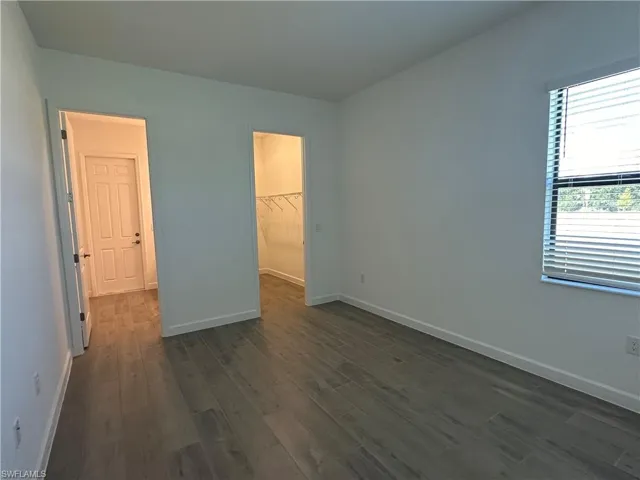 Unfurnished bedroom with dark hardwood / wood-style flooring, a closet, and a spacious closet
