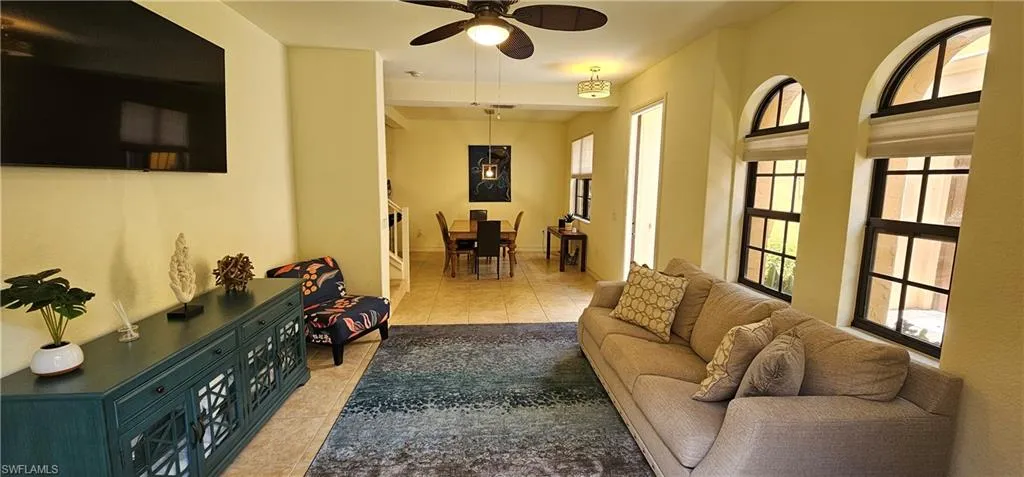 Living room with light tile patterned floors, healthy amount of natural light, and ceiling fan
