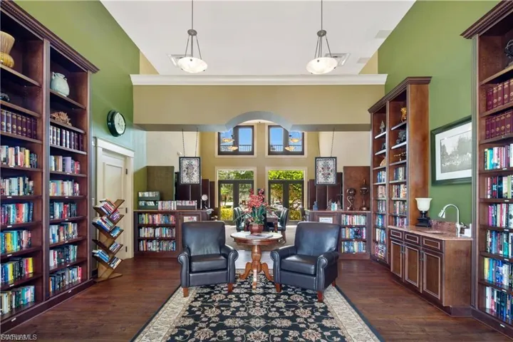 Sitting room with wall of books, ornamental molding, and dark wood-type flooring