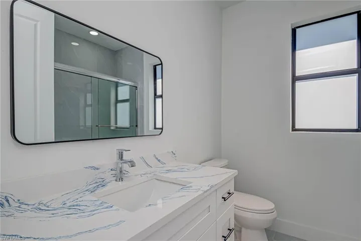 Full bath featuring plenty of natural light, a shower stall, toilet, and vanity