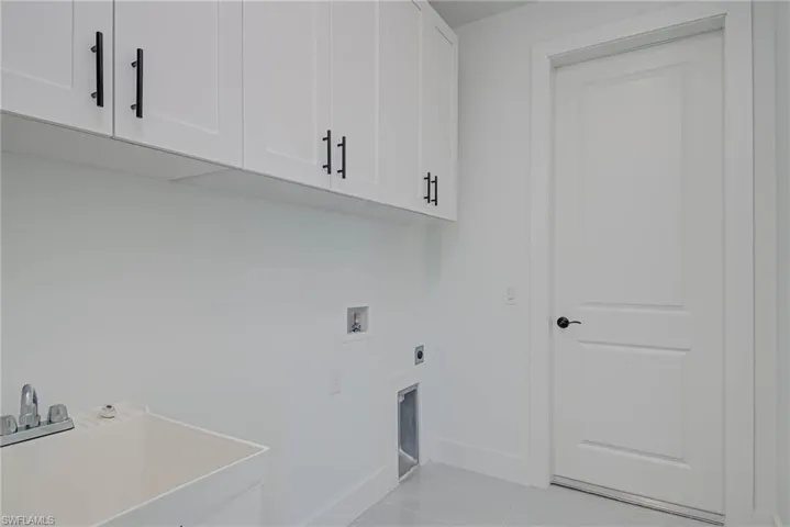 Laundry room with baseboards, hookup for an electric dryer, cabinet space, a sink, and washer hookup