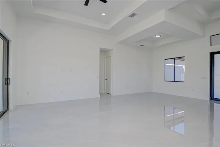 Spare room with visible vents, baseboards, a tray ceiling, and a ceiling fan