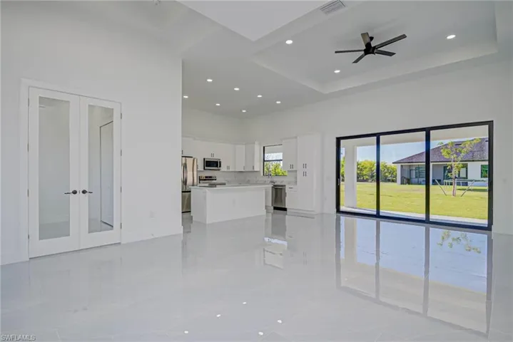 Unfurnished living room featuring visible vents, a ceiling fan, a tray ceiling, french doors, and a towering ceiling