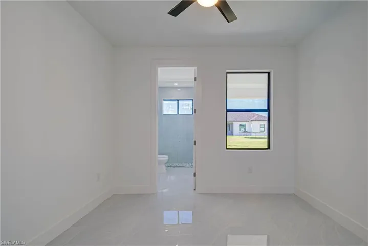 Empty room featuring a ceiling fan and baseboards