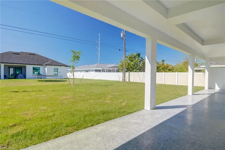 View of yard with fence, a trampoline, and a patio area
