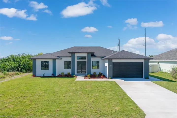 Prairie-style house with driveway, a shingled roof, stucco siding, a front lawn, and a garage