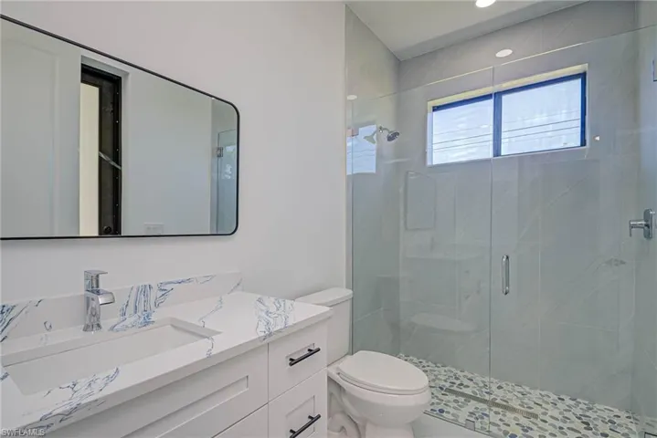 Bathroom featuring a stall shower, toilet, and vanity