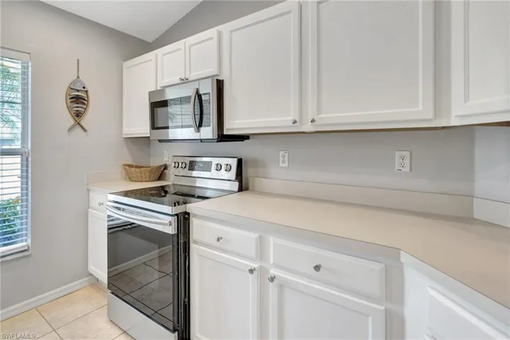Kitchen with light countertops, white cabinetry, light tile patterned flooring, and stainless steel appliances
