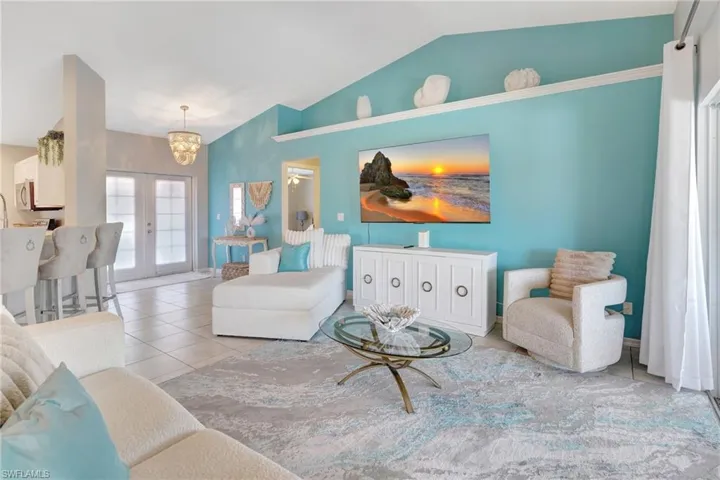 Tiled living room featuring french doors, a notable chandelier, and lofted ceiling
