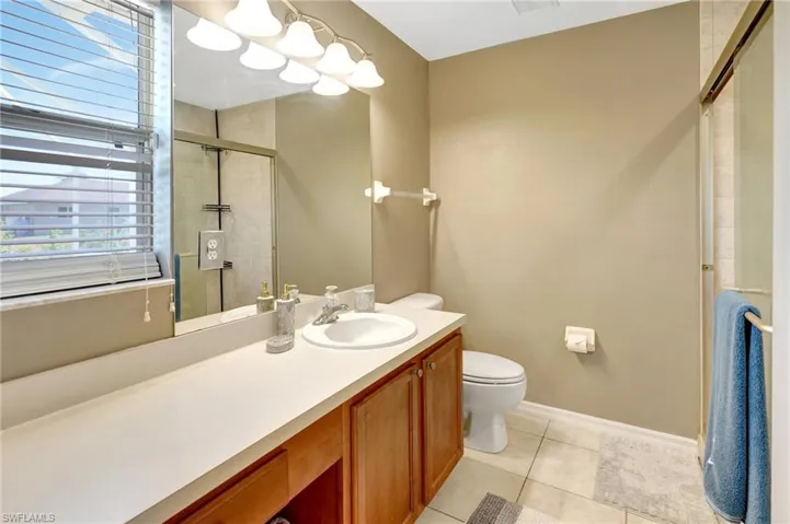 Bathroom featuring a shower stall, vanity, tile patterned flooring, toilet, and baseboards