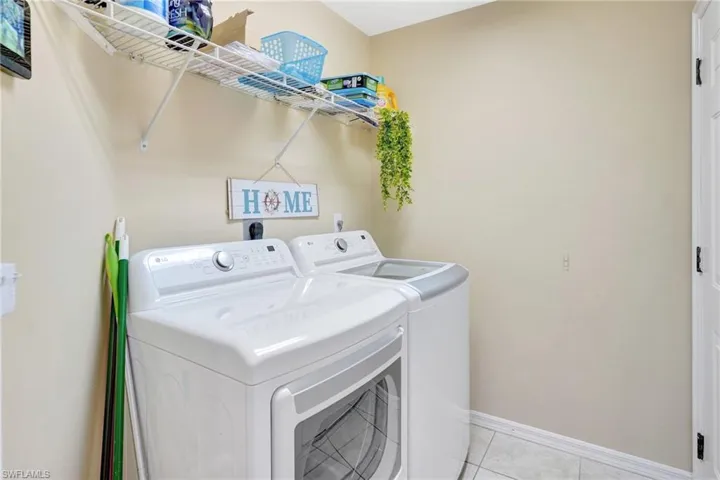 Laundry area featuring laundry area, washing machine and clothes dryer, baseboards, and light tile patterned floors
