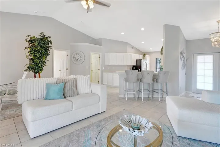 Living area with light tile patterned floors, vaulted ceiling, and a wealth of natural light