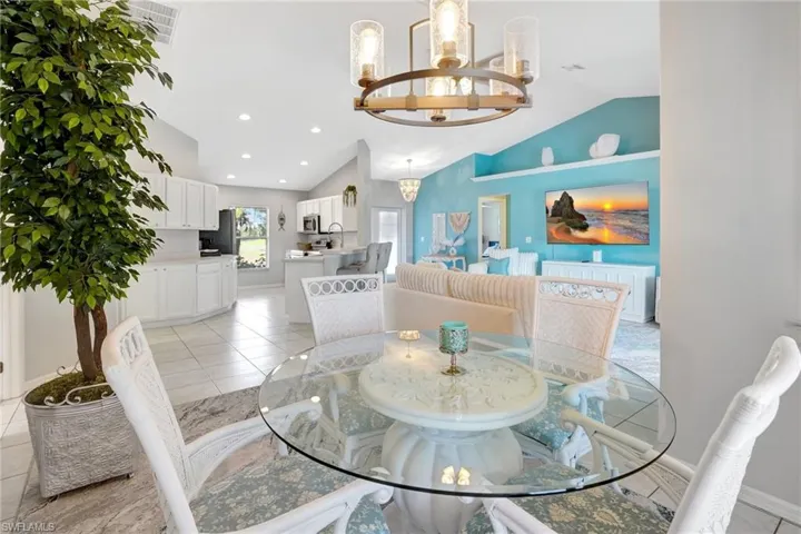 Dining area with baseboards, an inviting chandelier, recessed lighting, light tile patterned floors, and high vaulted ceiling