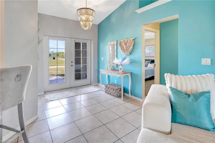 Doorway to outside with tile patterned flooring, french doors, baseboards, and an inviting chandelier